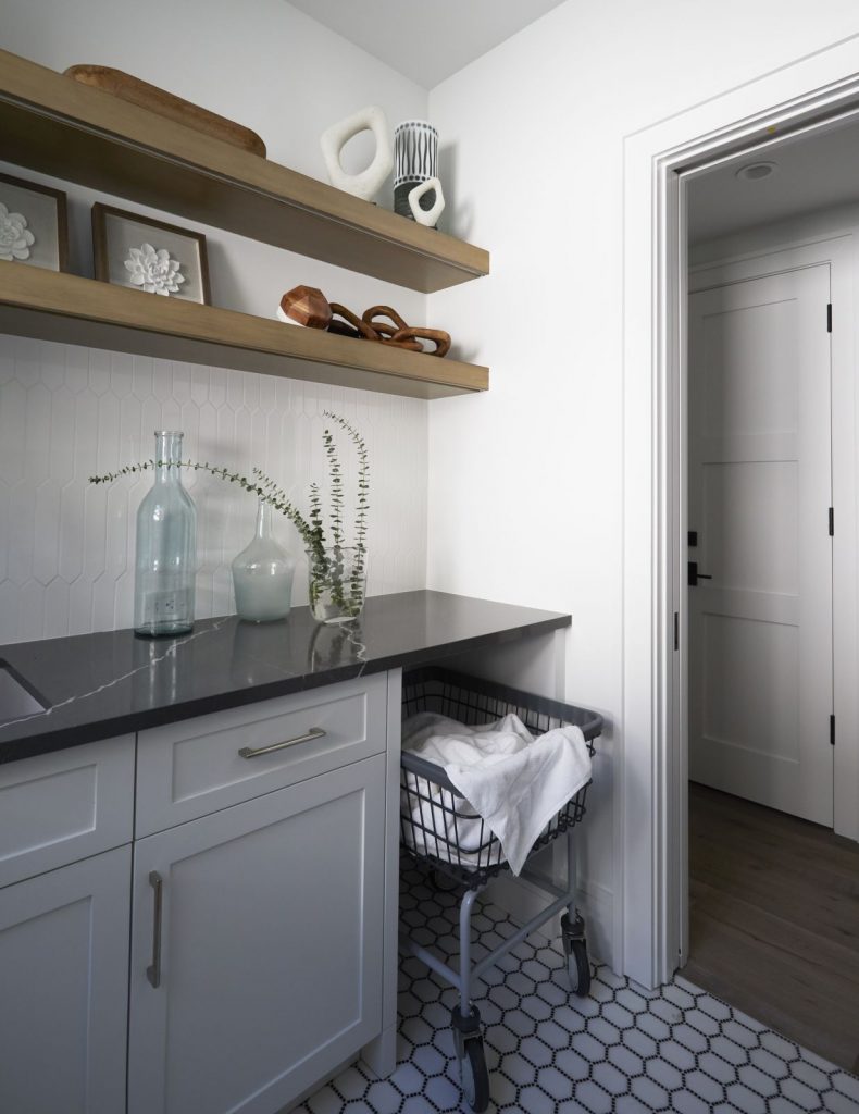 Laundry room with white cabinets and dark countertops and rolling basket Naples Florida